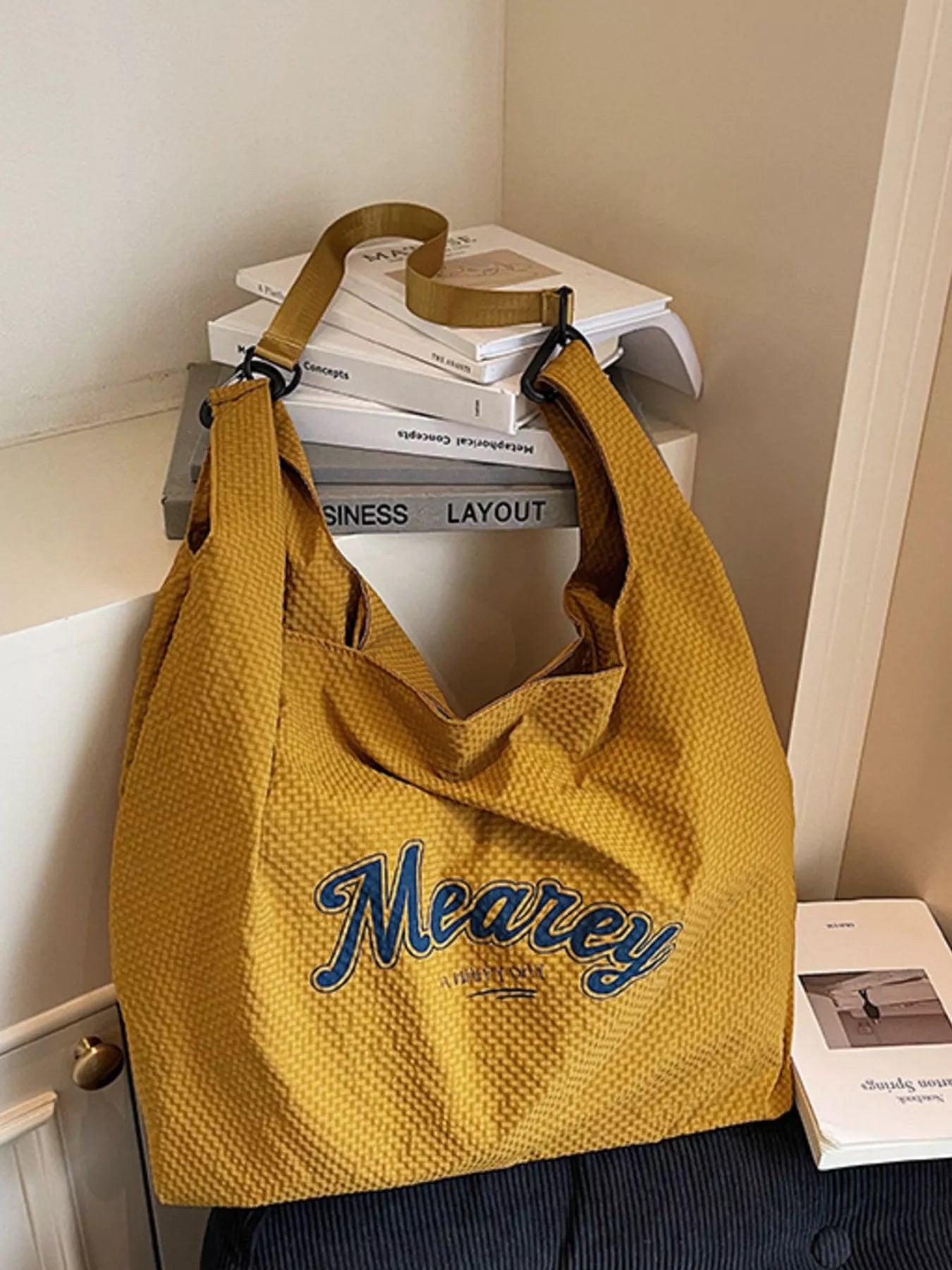 Yellow bag with 'Meaney' branding on a surface with books