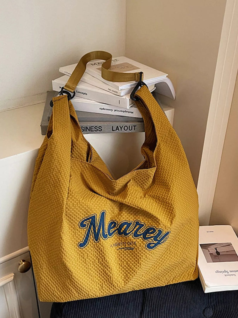 Yellow bag with 'Meaney' branding on a surface with books