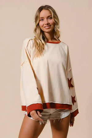 Woman wearing a white long-sleeve top with red accents and star patterns on a beige background