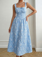 Woman wearing a blue floral dress against a neutral background