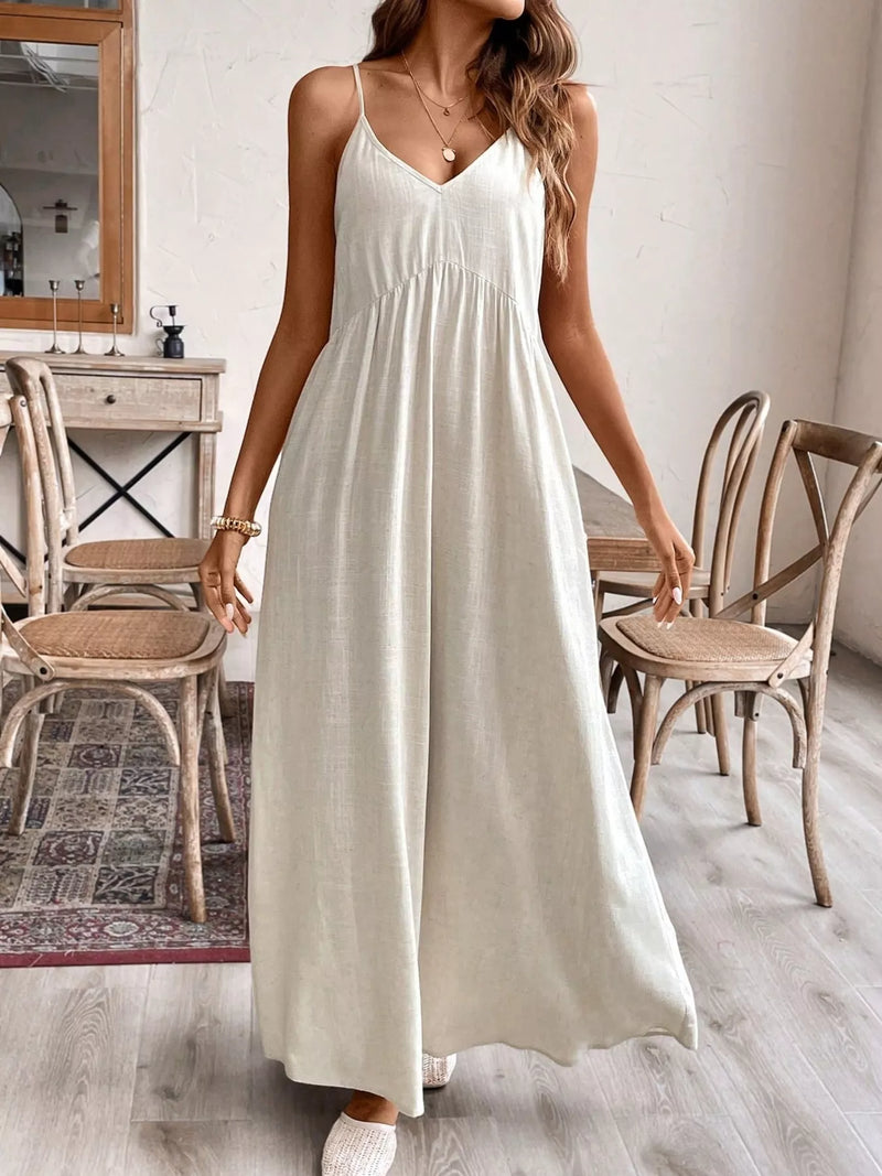 Woman wearing a white dress in a room with wooden chairs and a mirror.