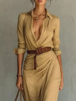 Woman wearing a beige jumpsuit with a brown belt against a gray background