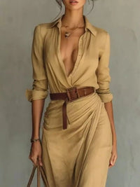 Woman wearing a beige jumpsuit with a brown belt against a gray background