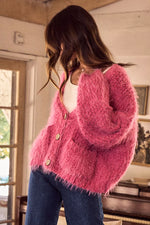 Person wearing a pink fuzzy cardigan in an indoor setting