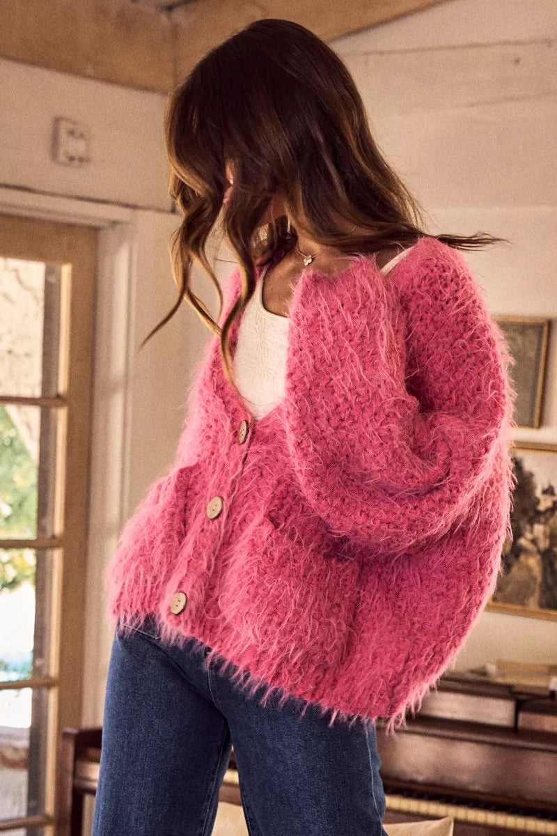 Person wearing a pink fuzzy cardigan in an indoor setting