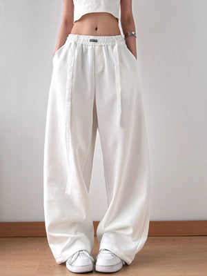 Person wearing white wide-leg pants and a white top on a plain background