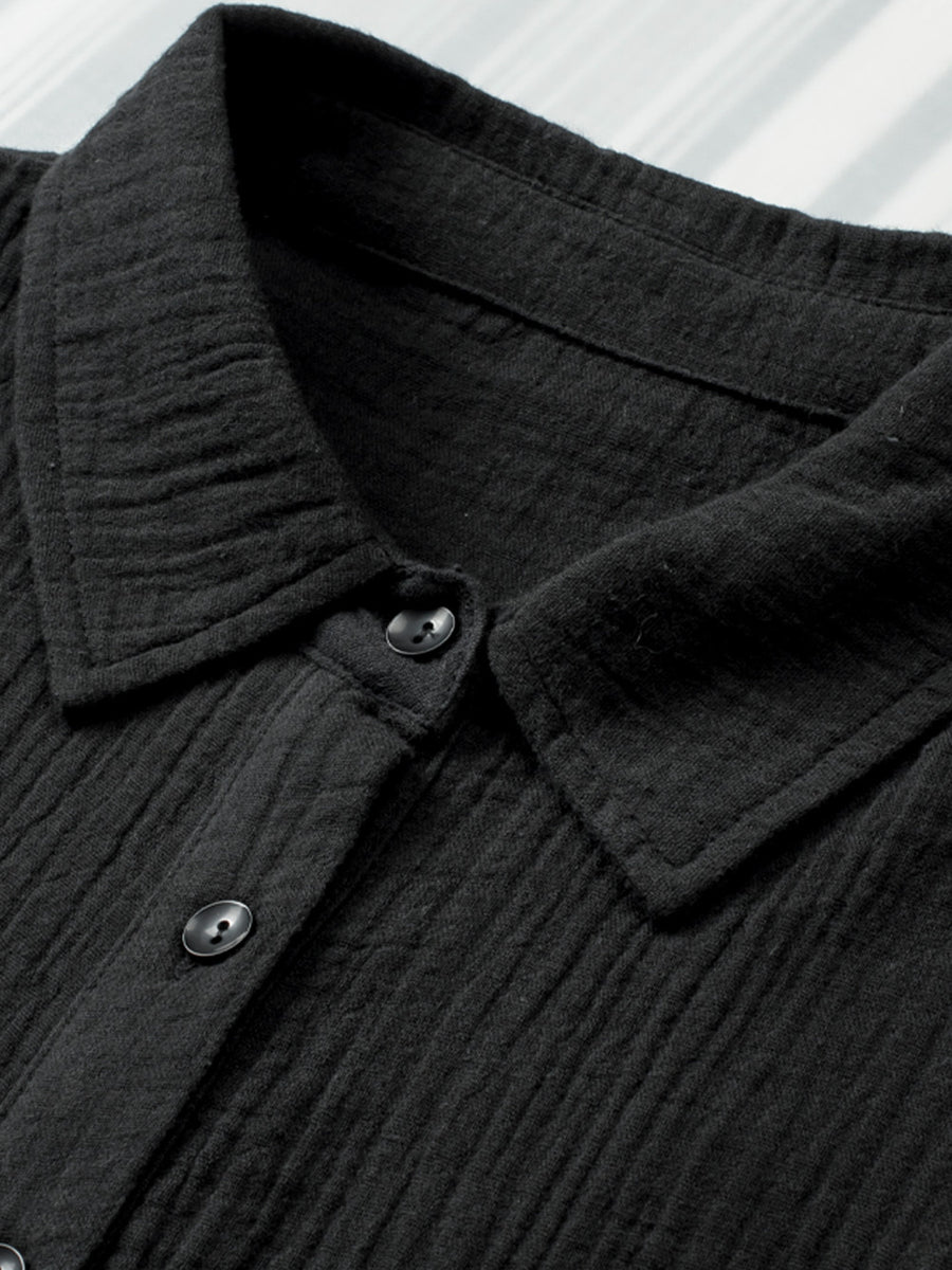 Close-up of a black textured shirt collar with buttons on a white background