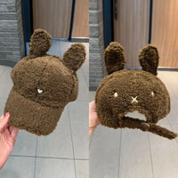 Brown fuzzy hat with bunny ears held in front of a mirror.