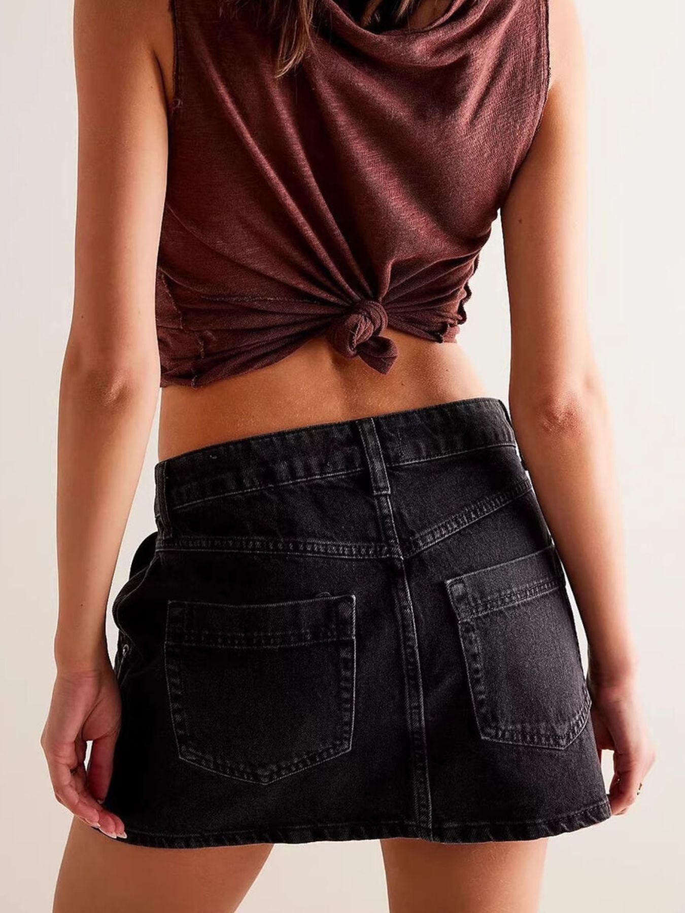 Person wearing a brown top and black skirt on a plain background