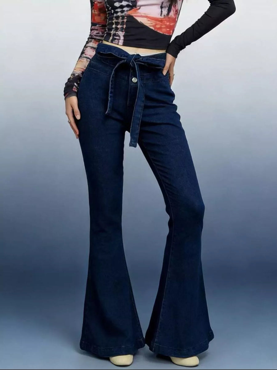 Person wearing blue flared jeans on a plain background