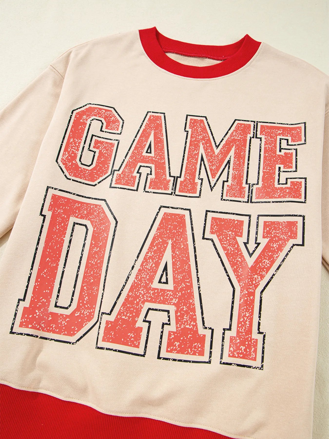 Sweatshirt with 'GAME DAY' text in red and black on a beige background