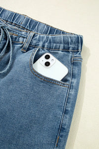 Blue jeans with a white phone in the pocket on a beige background