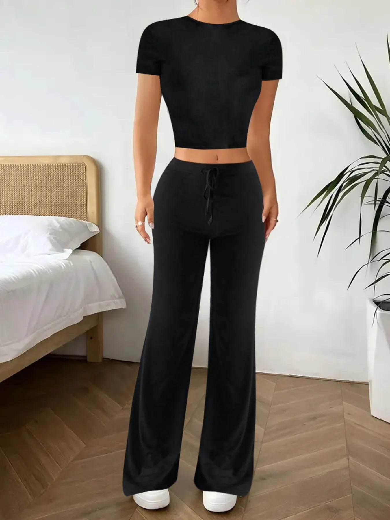 Person wearing a black outfit in a bedroom setting