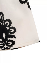 Close-up of a white garment with black floral patterns on a white background
