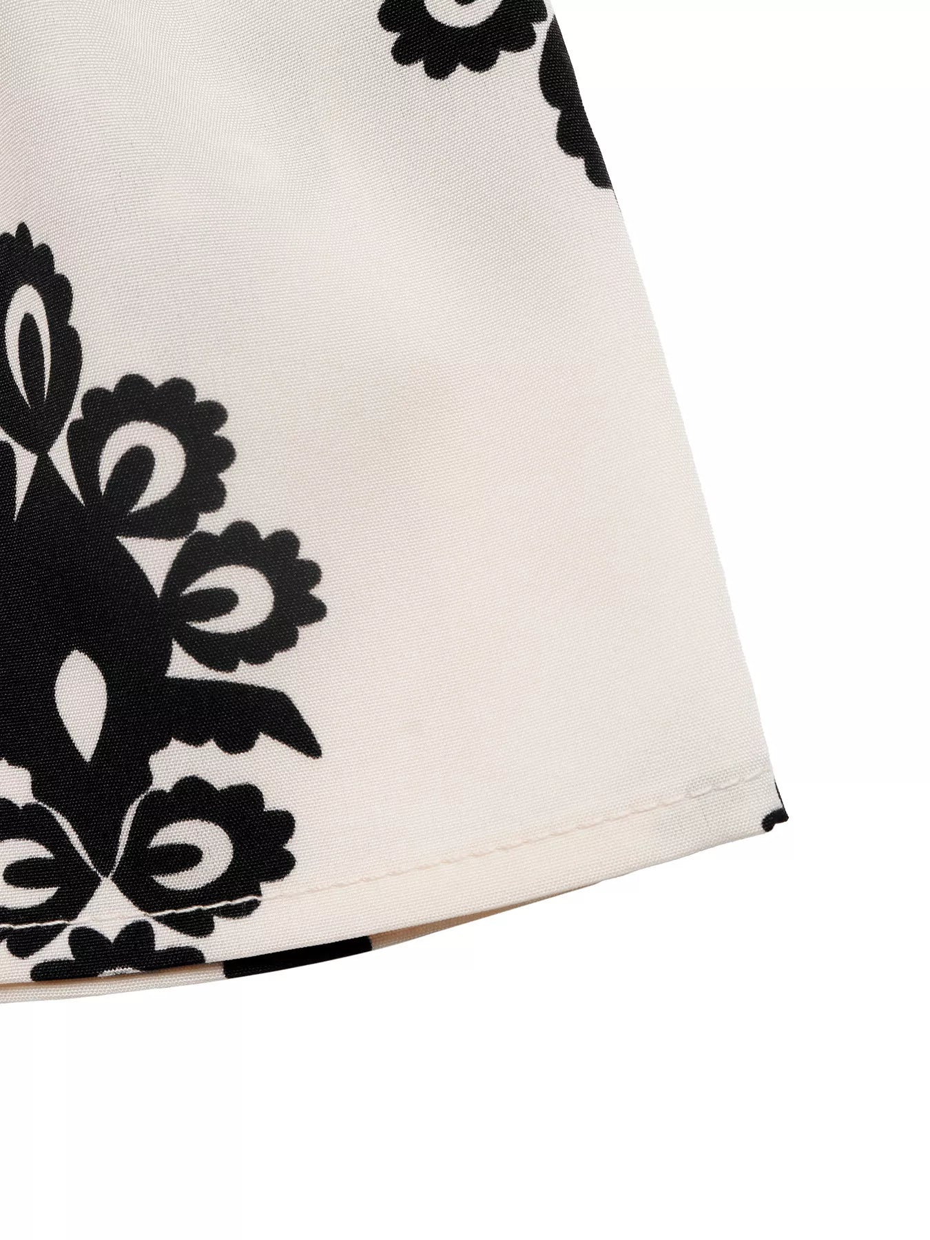 Close-up of a white garment with black floral patterns on a white background