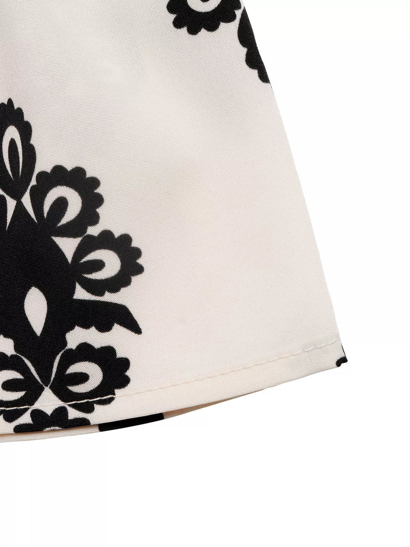 Close-up of a white garment with black floral patterns on a white background