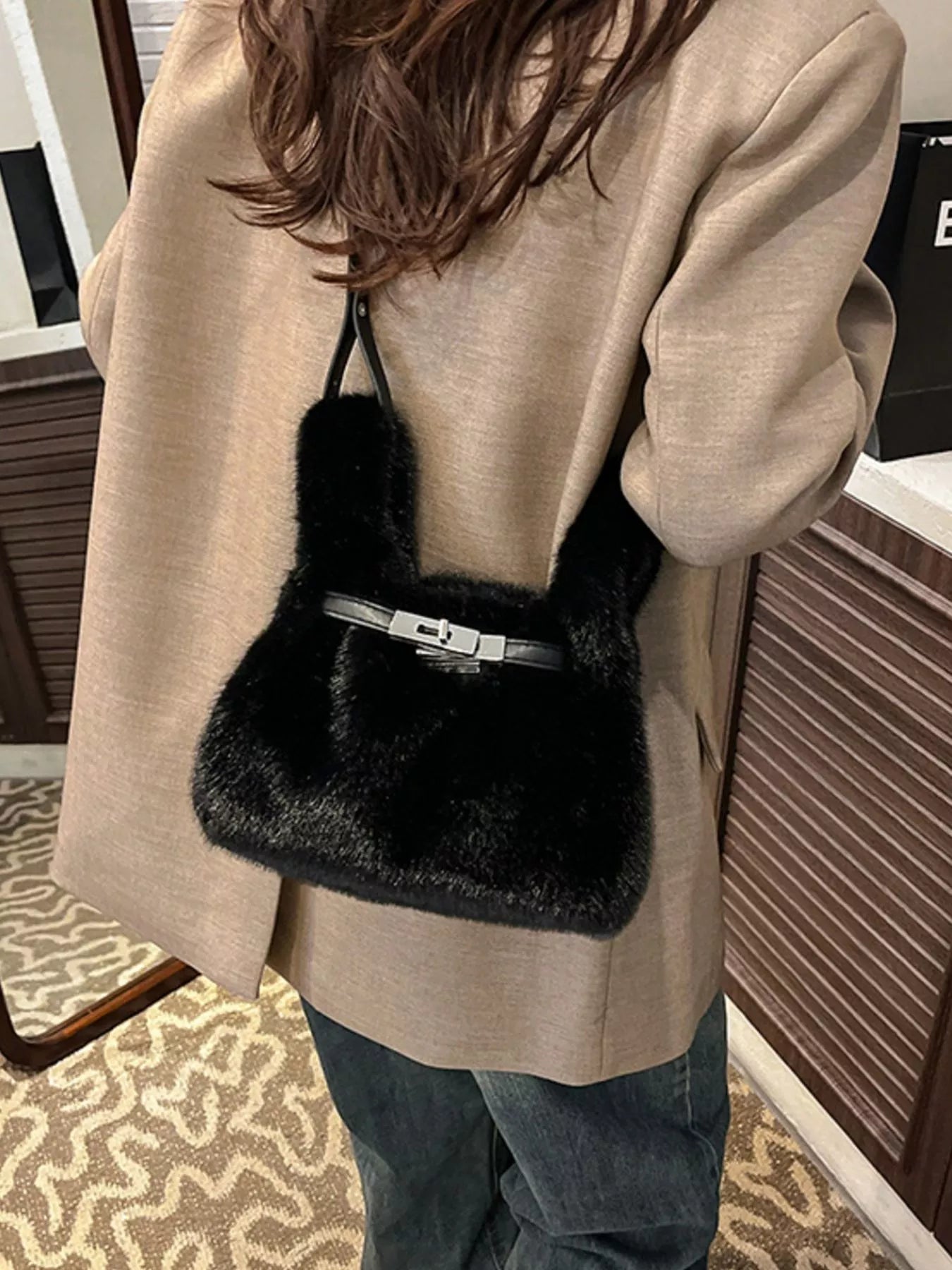 Person wearing a beige coat with a black fur-trimmed handbag.