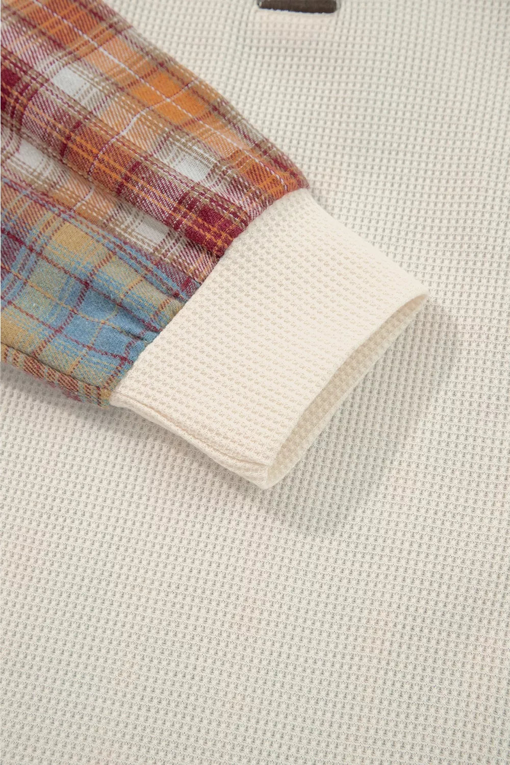 Close-up of a plaid fabric edge on a textured beige background