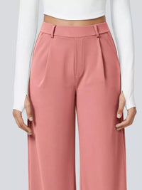 Pink pants worn with a white long-sleeve top on a light gray background