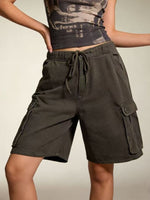 Person wearing dark green cargo shorts on a neutral background