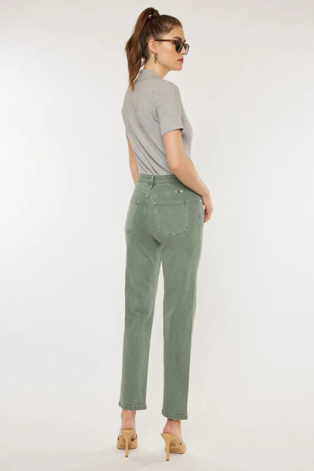 Woman wearing a gray t-shirt and green pants on a white background