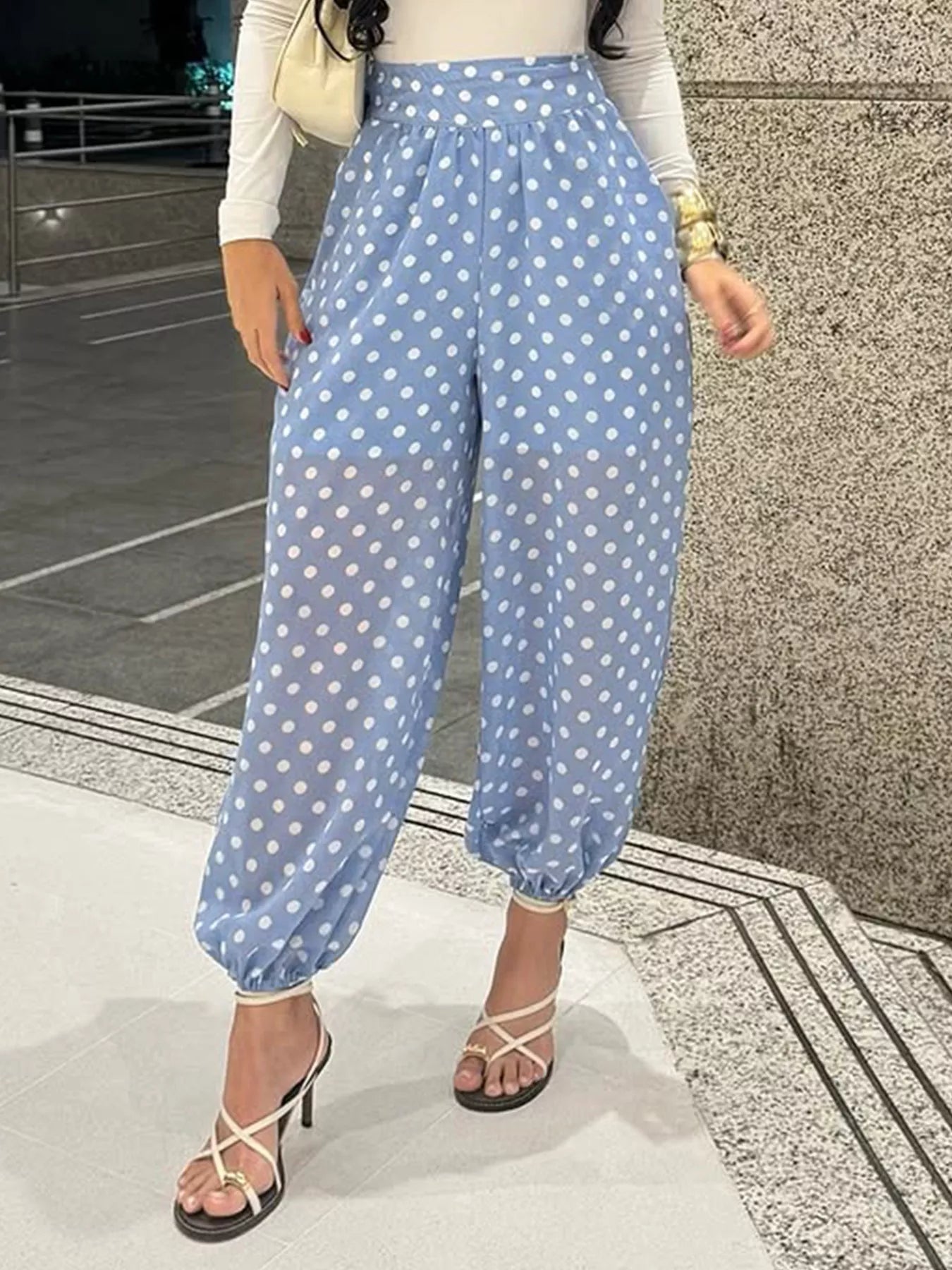 Person wearing blue polka dot pants standing on a tiled floor.