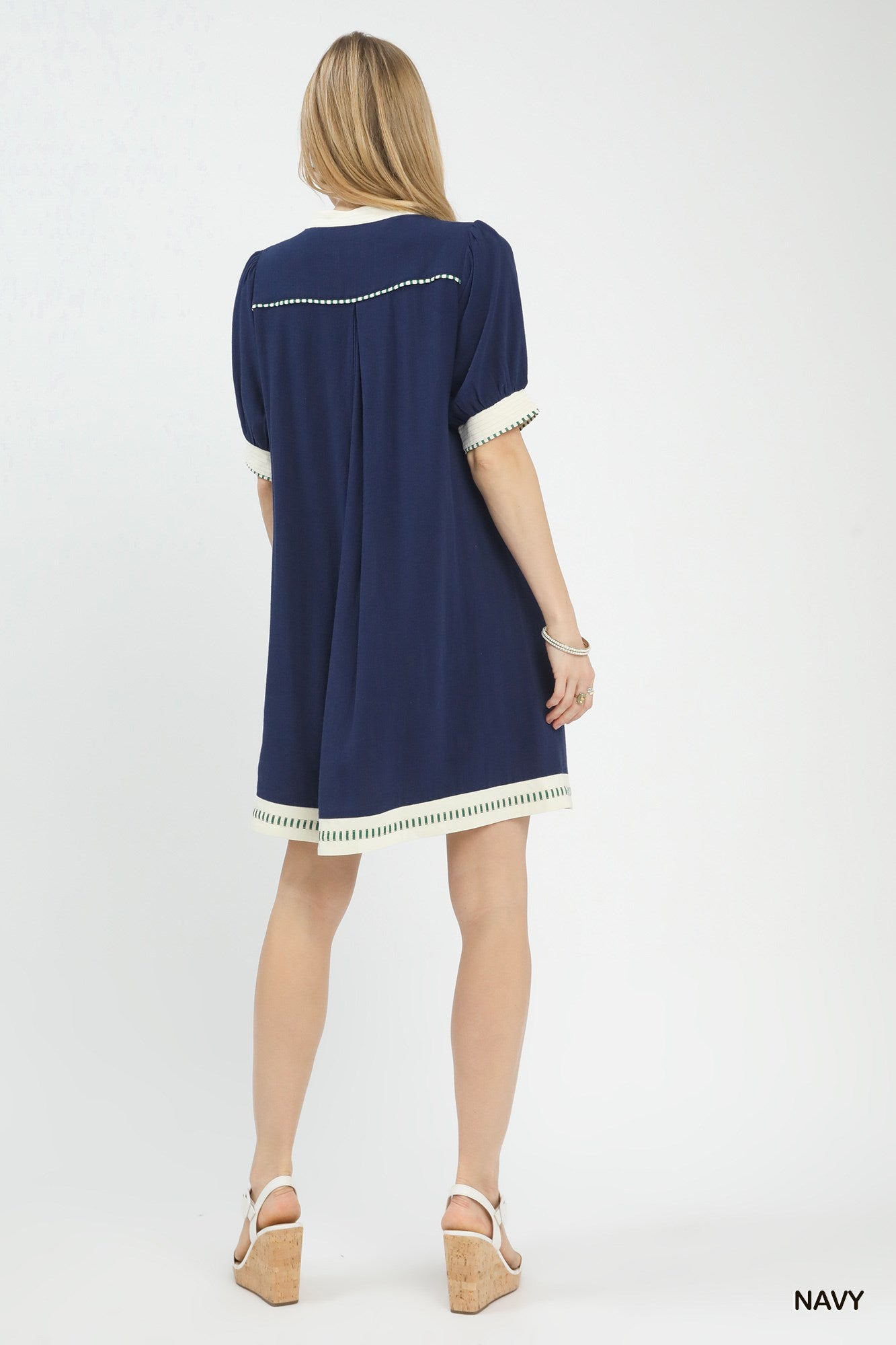 Woman wearing a navy dress with white trim on a white background