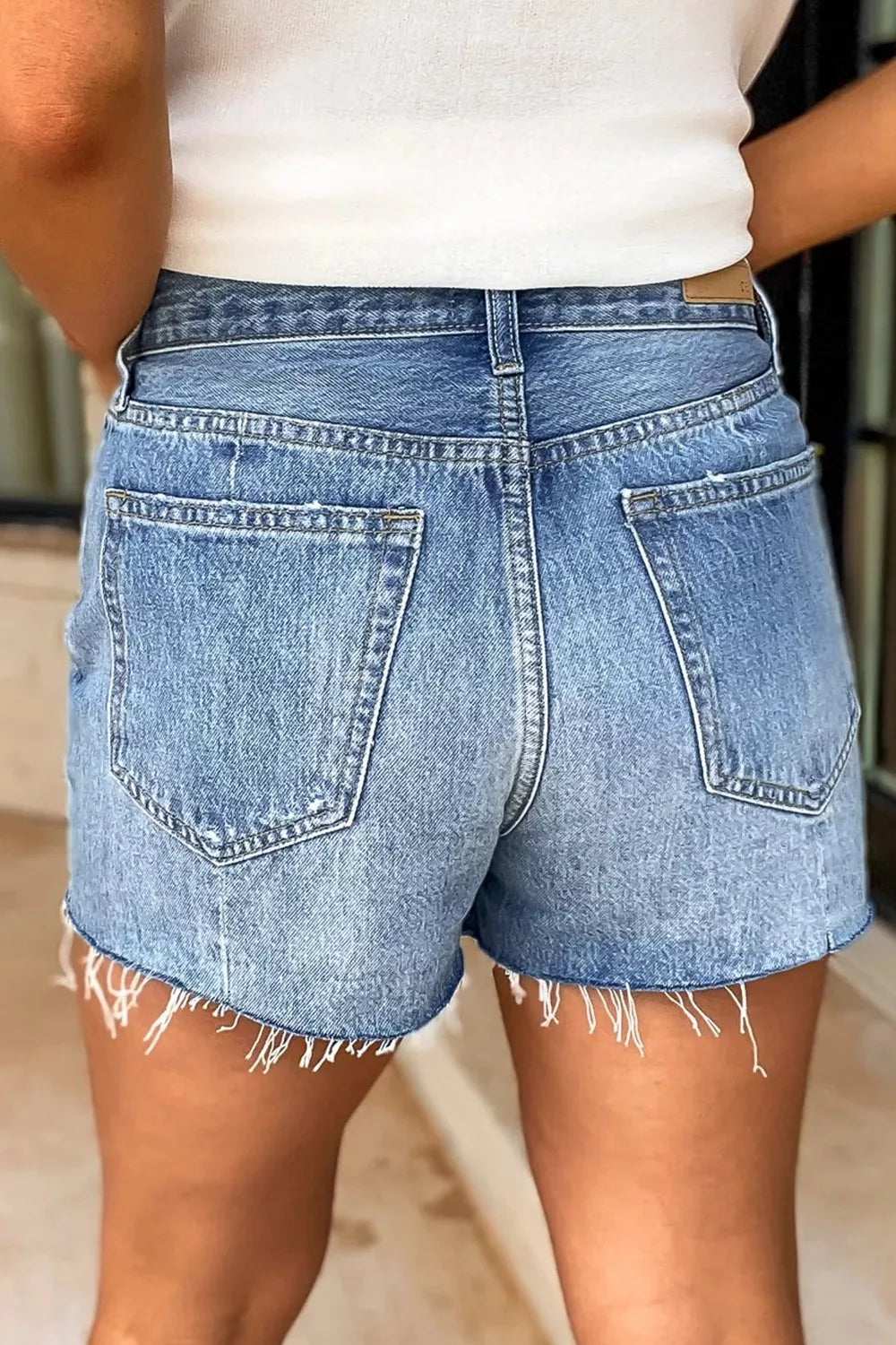 Person wearing light blue denim shorts with a white top.
