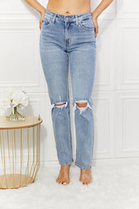 Person wearing light blue ripped jeans against a white background