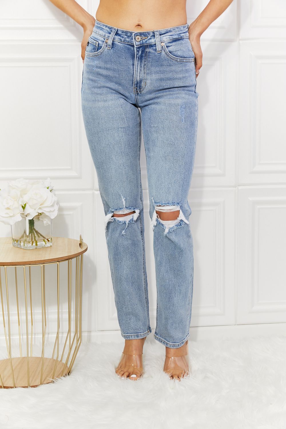 Person wearing light blue ripped jeans against a white background