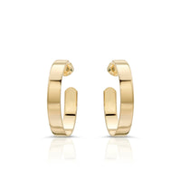 A pair of flat recycled brass hoop earrings with a 1 inch diameter, designed in a minimalistic style with a 14K yellow gold and rhodium finish.