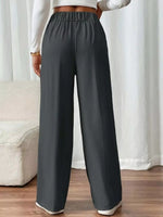 Person wearing gray wide-leg pants with a white background
