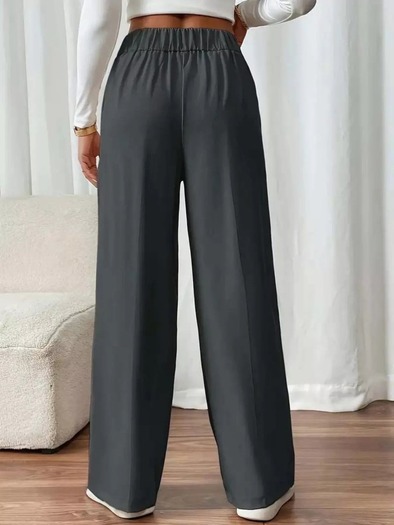 Person wearing gray wide-leg pants with a white background