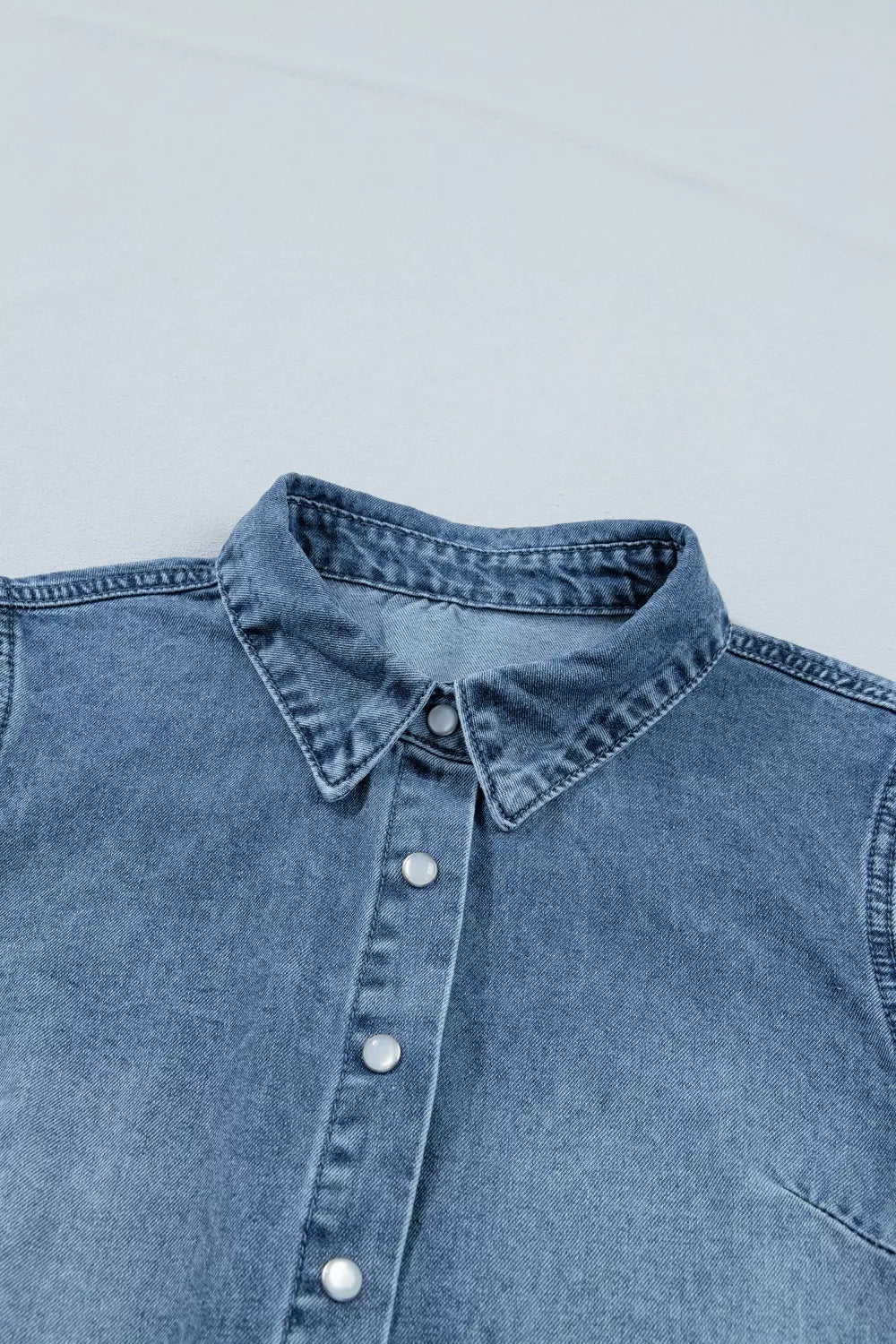 Blue denim shirt collar and buttons on a light gray background