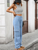 Person wearing a black and white striped crop top and light blue cargo pants on a street.
