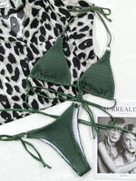 Green bikini set on a white surface with a leopard print fabric in the background.