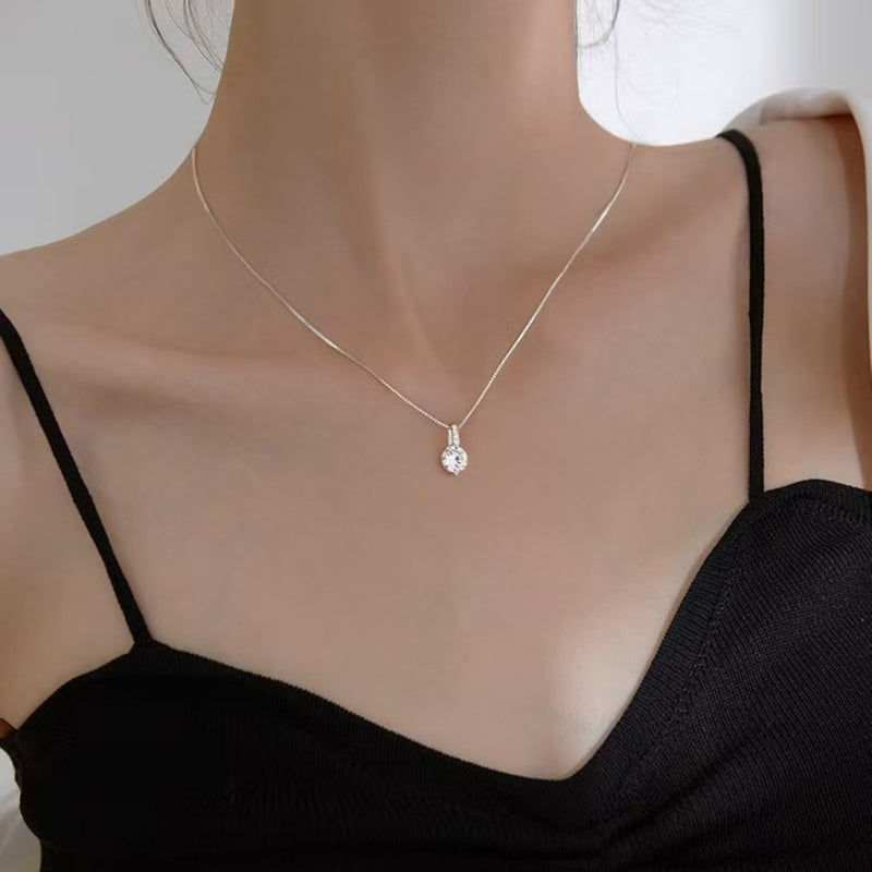 Necklace with a pendant on a mannequin wearing a black top against a neutral background