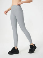Person wearing gray leggings and black sneakers on a white background