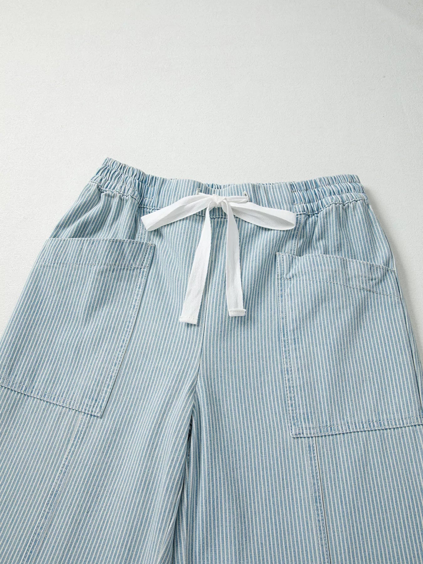 Light blue striped pants with a drawstring on a light gray background