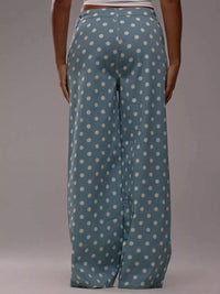 Blue pants with white polka dots worn by a person on a gray background