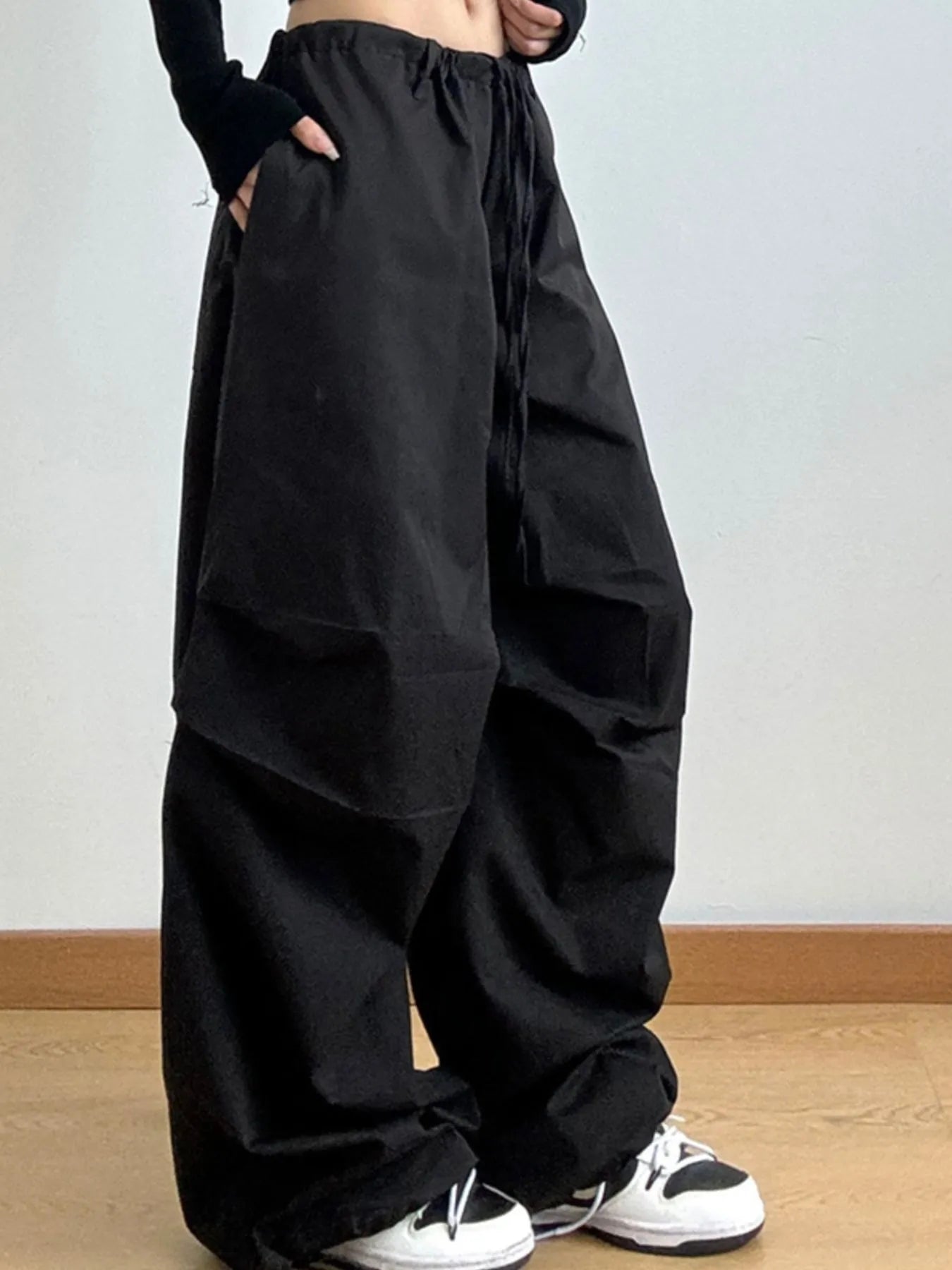 Person wearing black wide-leg pants on a plain background