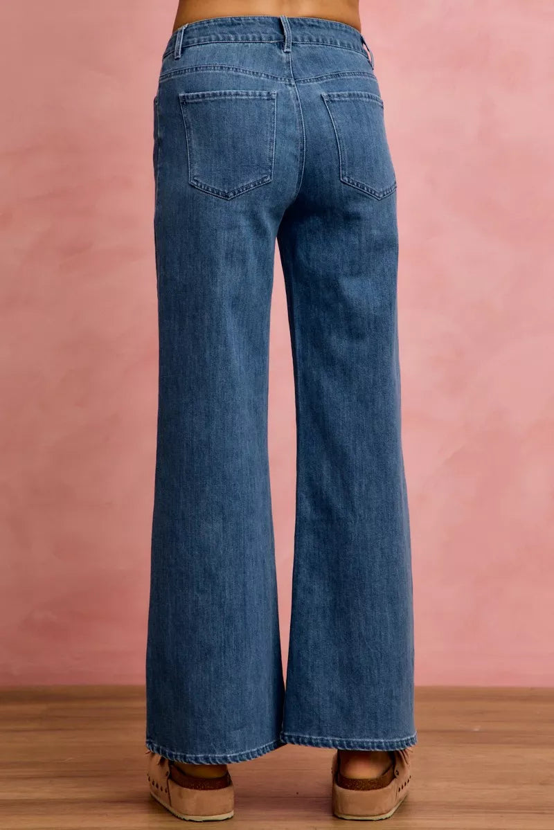 Blue jeans worn by a person on a pink background