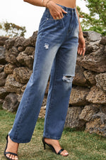 Person wearing blue jeans with a stone wall and grass background