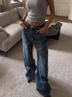 Person wearing a gray tank top and blue jeans in a living room.