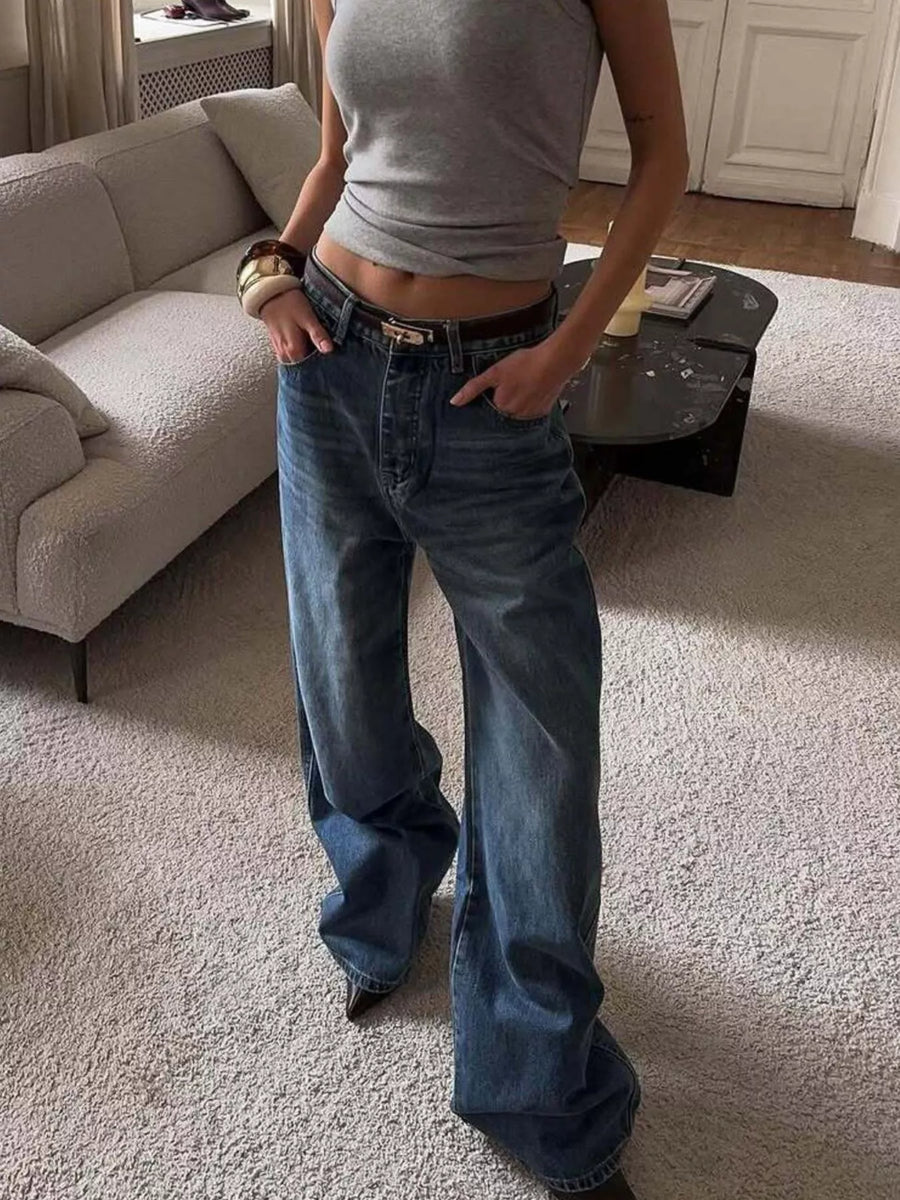 Person wearing a gray tank top and blue jeans in a living room.