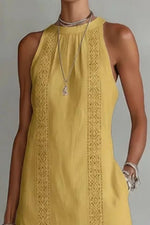 Yellow sleeveless dress with intricate detailing on a plain background