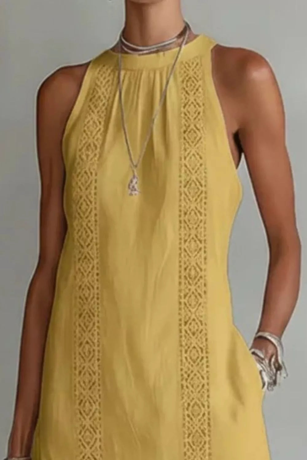 Yellow sleeveless dress with intricate detailing on a plain background