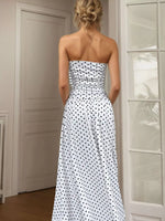 Woman wearing a strapless polka dot dress in a room with neutral walls and a door.