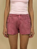 Person wearing pink shorts and a white top on a beige background