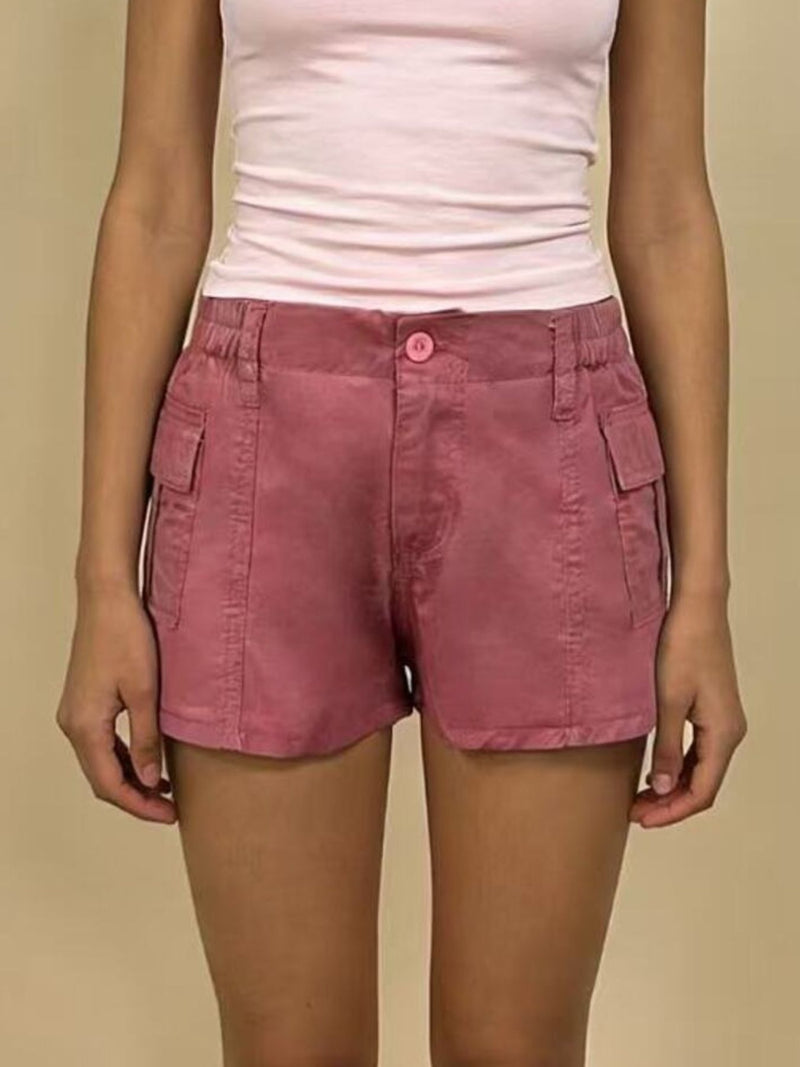 Person wearing pink shorts and a white top on a beige background
